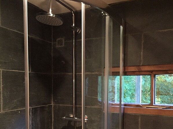 A modern shower with a glass enclosure and a view of the outdoors through a window. - Faraway Follies (Wrexham)