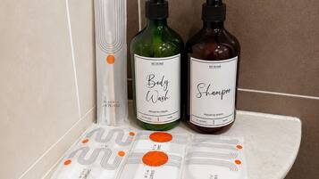 A bathroom shelf with two bottles of body wash and shampoo, a towel, and a shower cap.