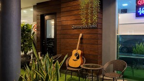 A hotel entrance with a guitar, chairs, and potted plants. - Royal Queenspark Hotel (Malacca City)