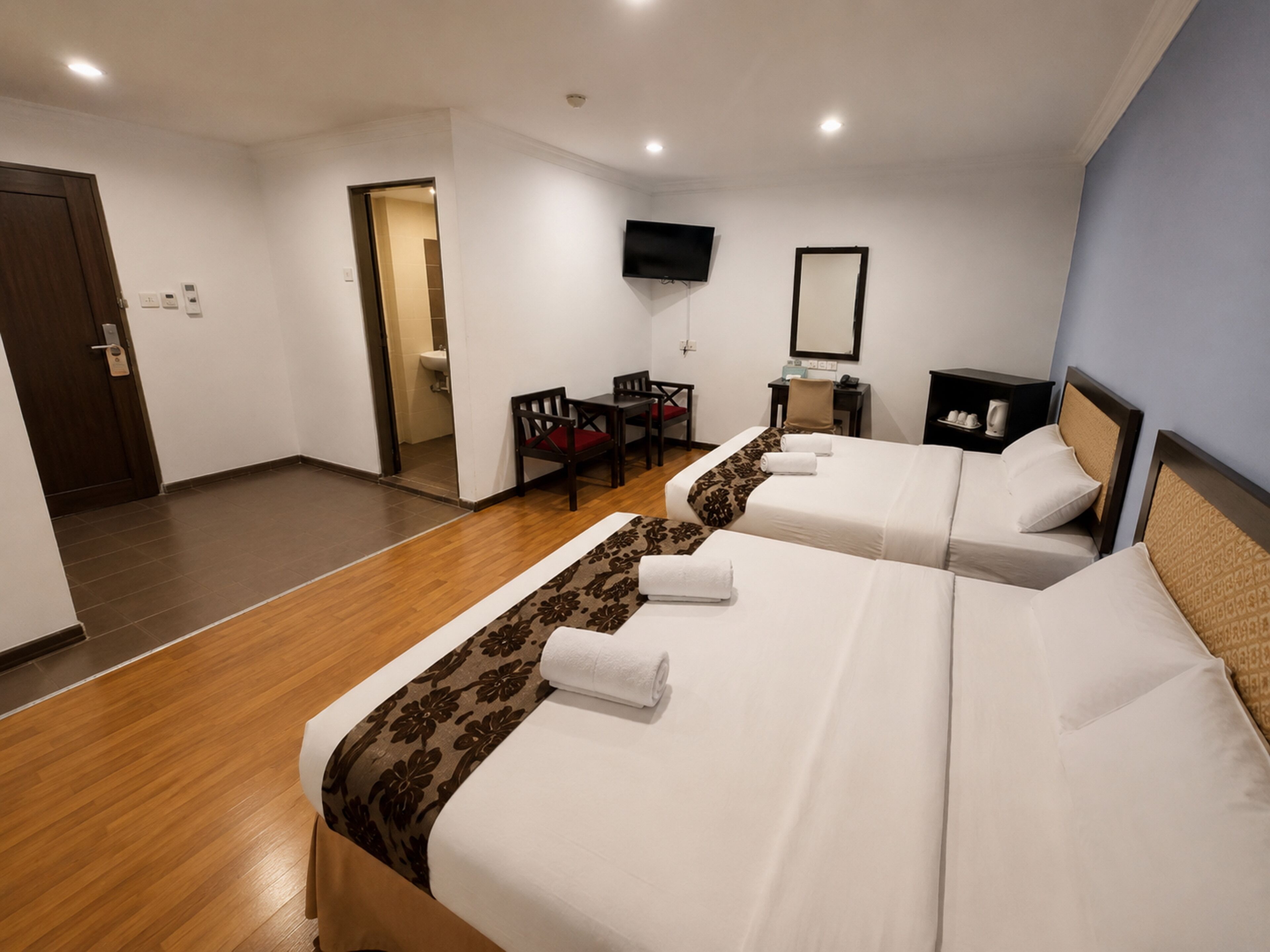 Een hotelkamer met twee bedden, een televisie, een bureau en een stoel.