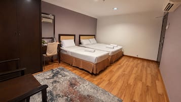A hotel room with two beds, a desk, a chair, a coffee maker, and an air conditioning unit.