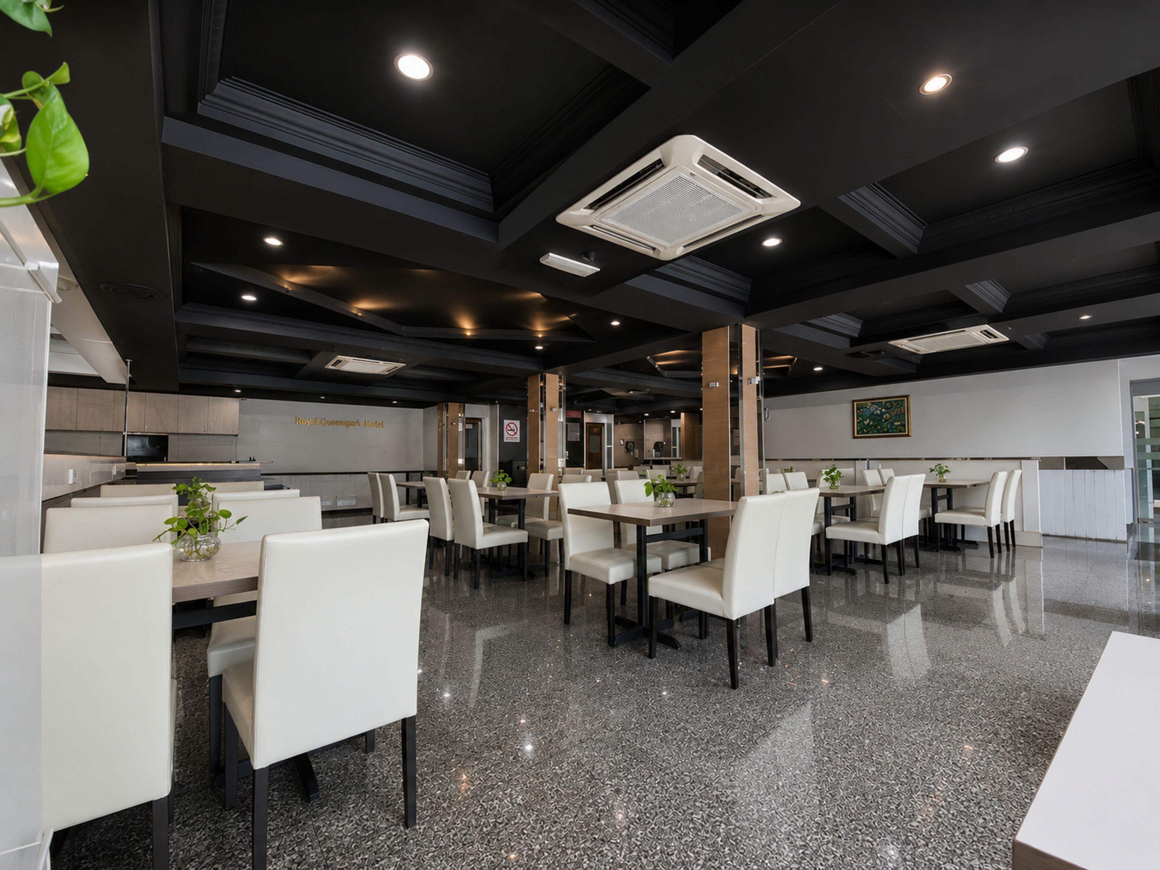 Un espace de restauration moderne dans un hôtel, avec des meubles blancs, un sol en granit et un éclairage encastré.