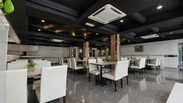 Un espace de restauration moderne dans un hôtel, avec des meubles blancs, un sol en granit et un éclairage encastré.