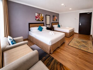 A hotel room with two beds, a sofa, a desk, and a door. - Royal Queenspark Hotel (Malacca City)