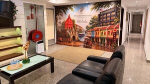 A hotel lobby with a large mural, a reception desk, a seating area, and a corridor. - Royal Queenspark Hotel (Malacca City)