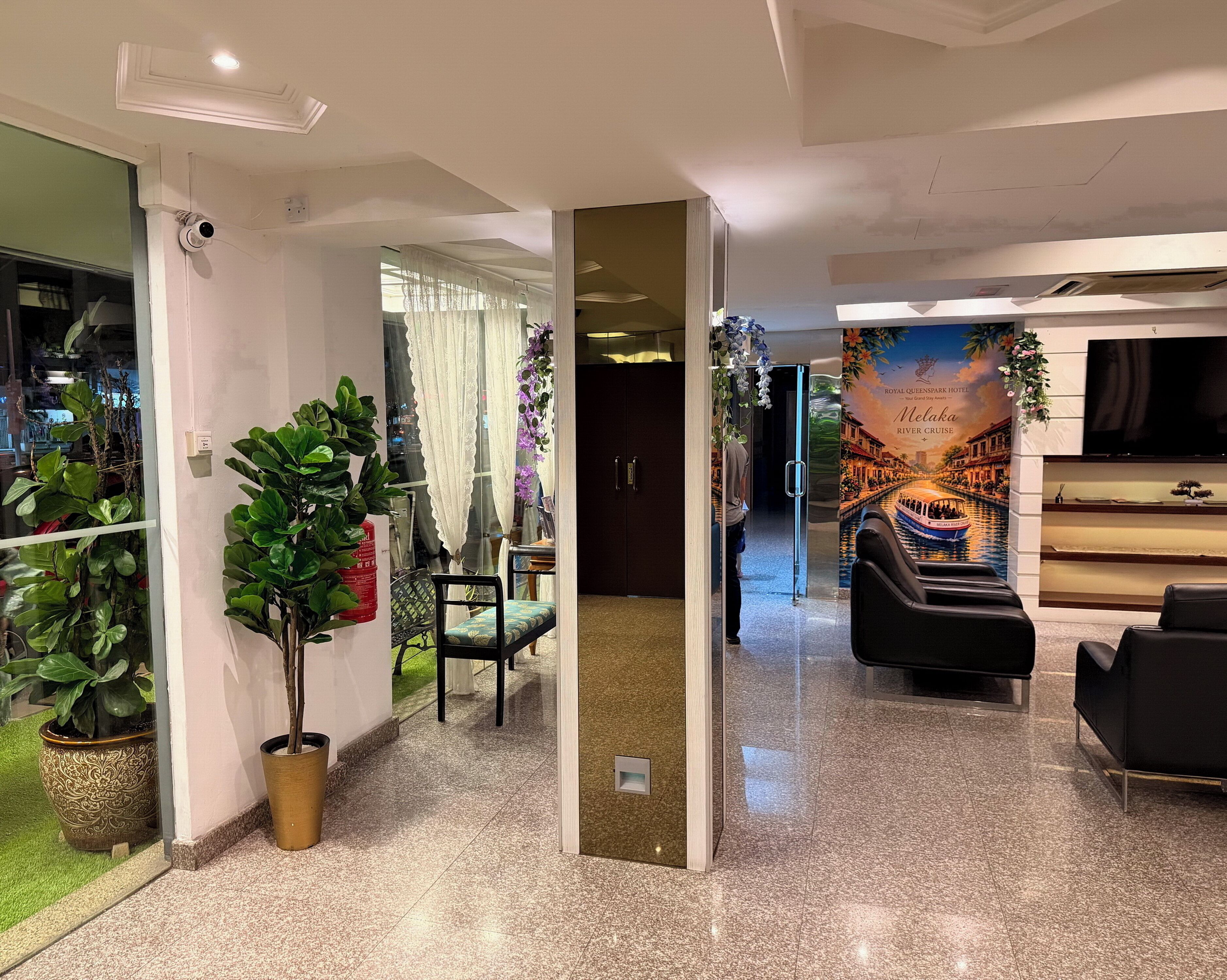 A hotel lobby with a reception desk, seating area, and a mural depicting a river cruise.