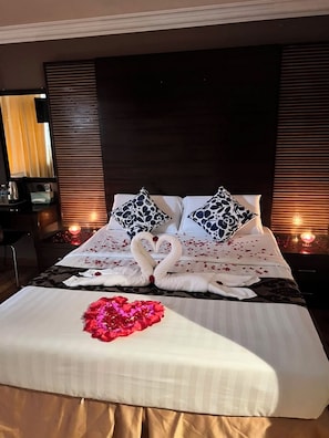 A hotel room with a large bed, two pillows, a bedside table, and a mirror. - Royal Queenspark Hotel (Malacca City)