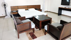 A hotel room with a bed, a desk, a chair, a sofa, a standing fan, and a TV. - Sky Hotel Nairobi (Nairobi)