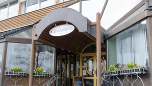 La entrada del Hotel Kumla, con un diseño moderno, presenta un arco pronunciado y una escalera que conduce a la entrada.