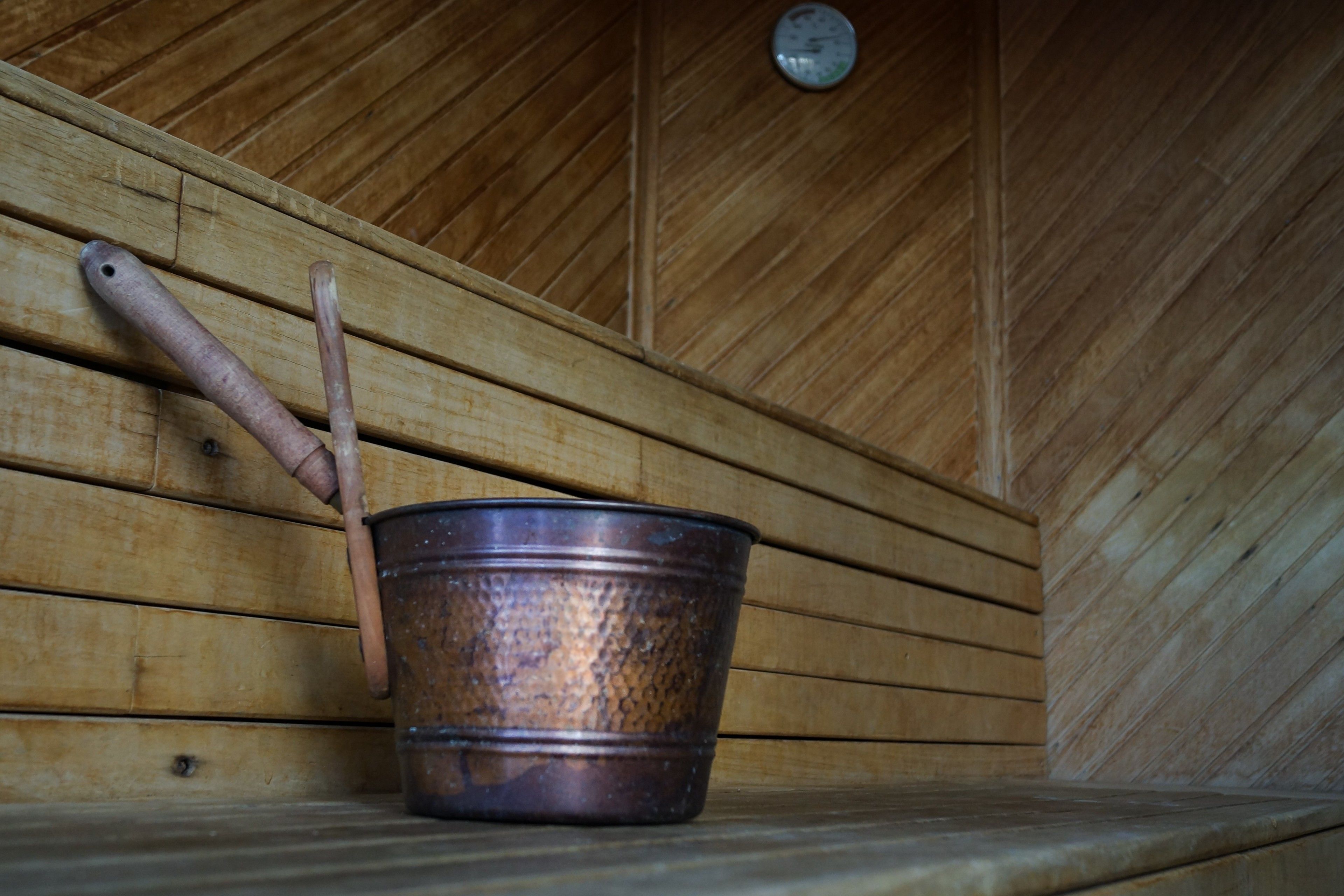 A rustic wooden interior with a metal bucket and wooden tools leaning against the wall.