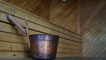 A rustic wooden interior with a metal bucket and wooden tools leaning against the wall.