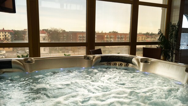 Un jacuzzi con vistas a edificios a través de amplias ventanas.