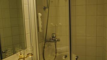 Un baño con ducha de vidrio, lavamanos con espejo y paredes de azulejos.