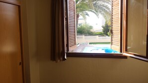A room with a window overlooking a swimming pool and a fenced yard. - Hostal Bahía Blanca (Alicante)