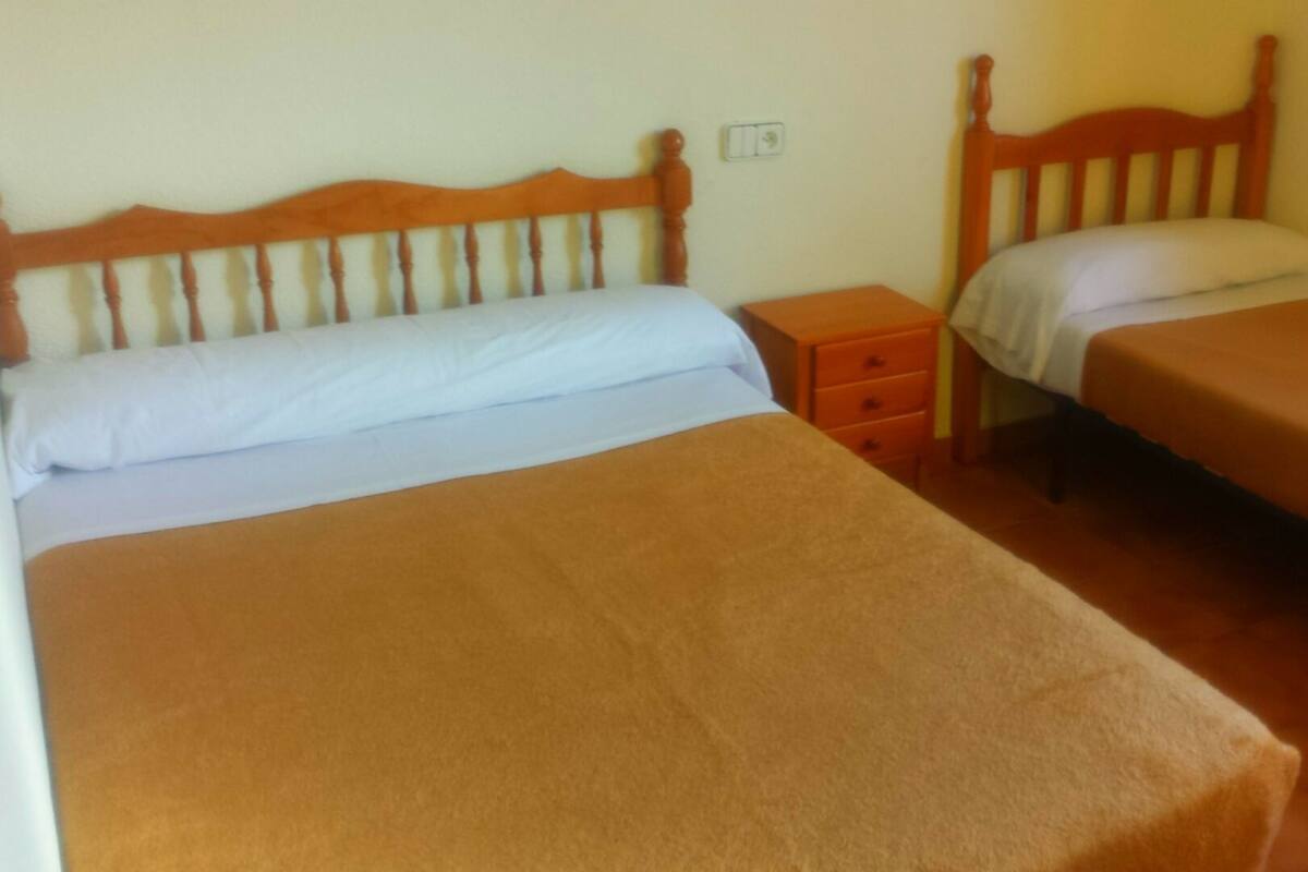 Una habitació amb dos llits individuals, cadascun amb un panell de fusta al capçal i una taula de nit.