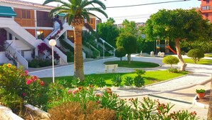 A courtyard with a palm tree, a bench, and a building with a staircase. - Hostal Bahía Blanca (Alicante)