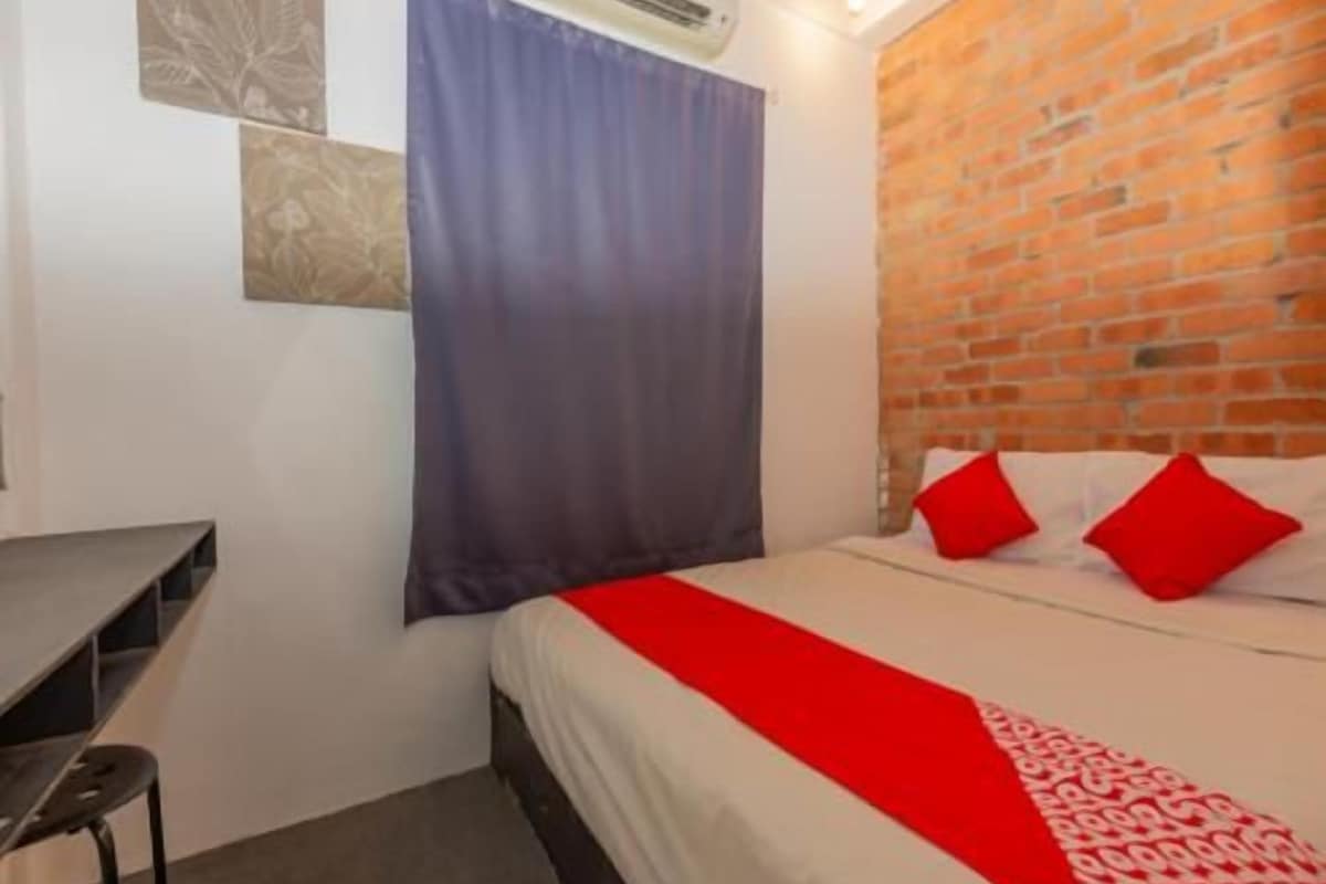 Una habitación con una cama, un escritorio y una pared de ladrillo.