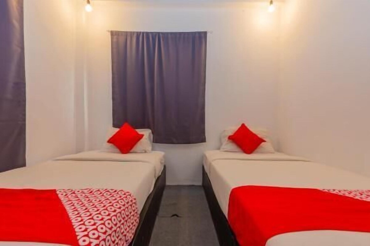 Una habitación con dos camas, cada una con un cojín rojo y una colcha estampada.