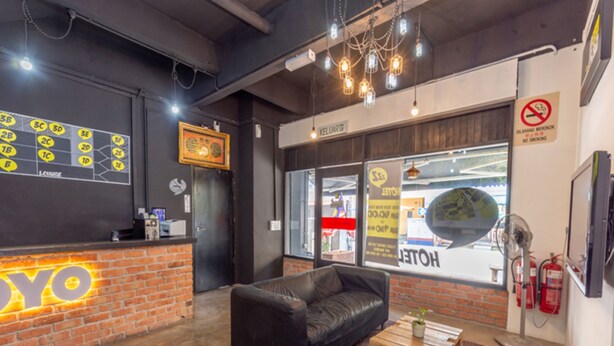Een moderne lobby met een receptiebalie van baksteen, een zwarte leren bank, een houten salontafel en een kamerbreed tapijt met een patroon.
