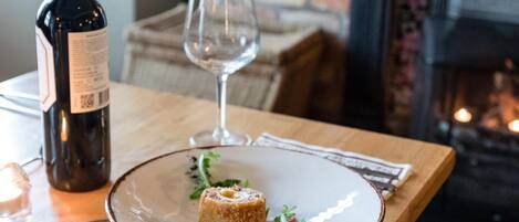 Une table avec une bouteille de vin, un verre et une assiette contenant un plat.