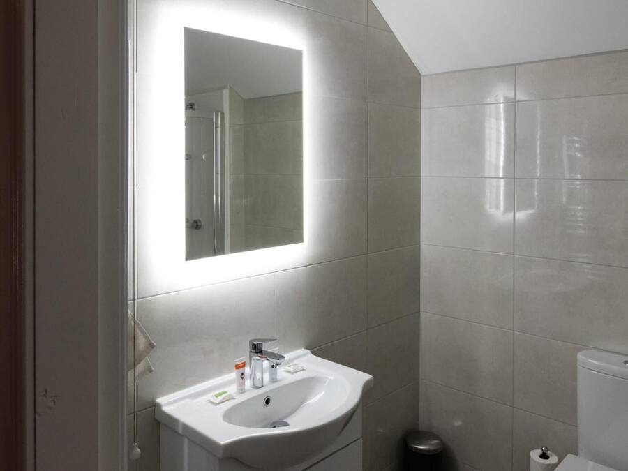 Un baño moderno con un lavamanos, espejo y retrete blancos.