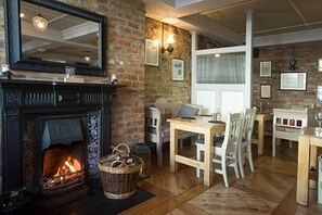A cozy room with a fireplace, wooden furniture, and a stone wall. - The Tailor's House (Dungannon)