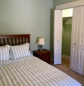 A bedroom with a bed, a nightstand, a lamp, and a closet. - 109 Main Street (Stowe)