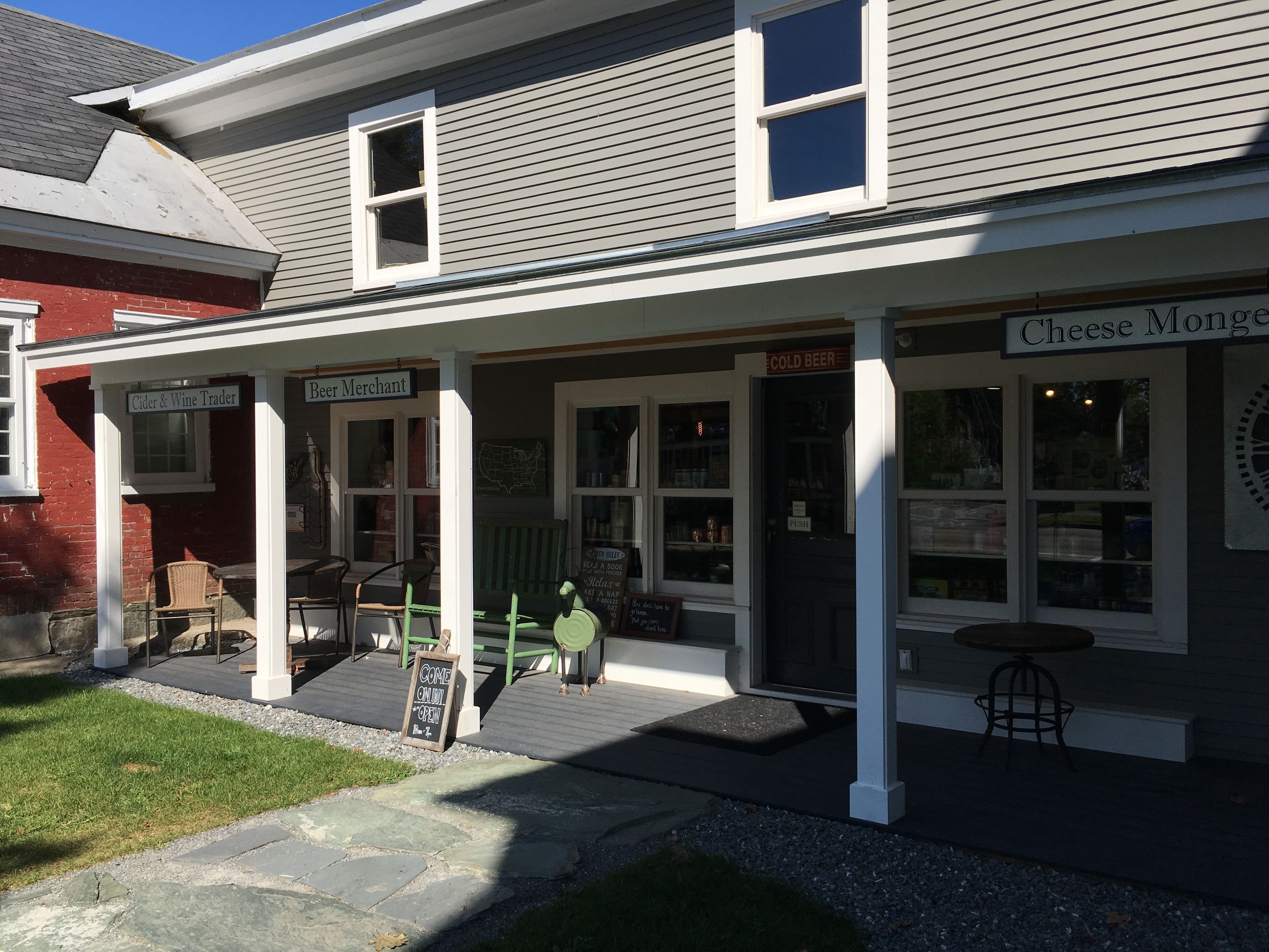 A building with a porch, a sign for 'Cider & Wine Trader', and a sign for 'Cheese Monger'.