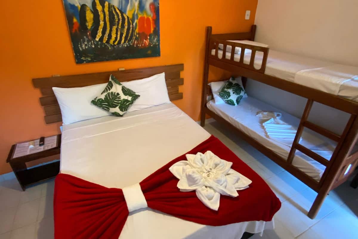 Una habitación de hotel con una cama individual, una litera, una pared naranja y un cuadro.