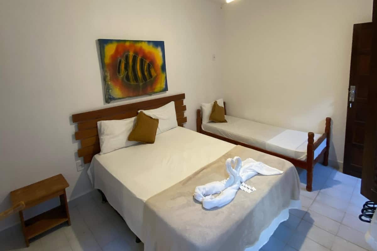 Habitación de hotel con una cama grande, una cama más pequeña, un ventilador de techo y un cuadro en la pared.