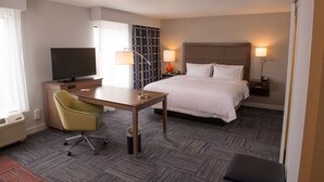 Une chambre d’hôtel équipée d’un lit, d’un bureau, d’une chaise, d’une télévision, de lampes et d’un mur décoré d’un motif.