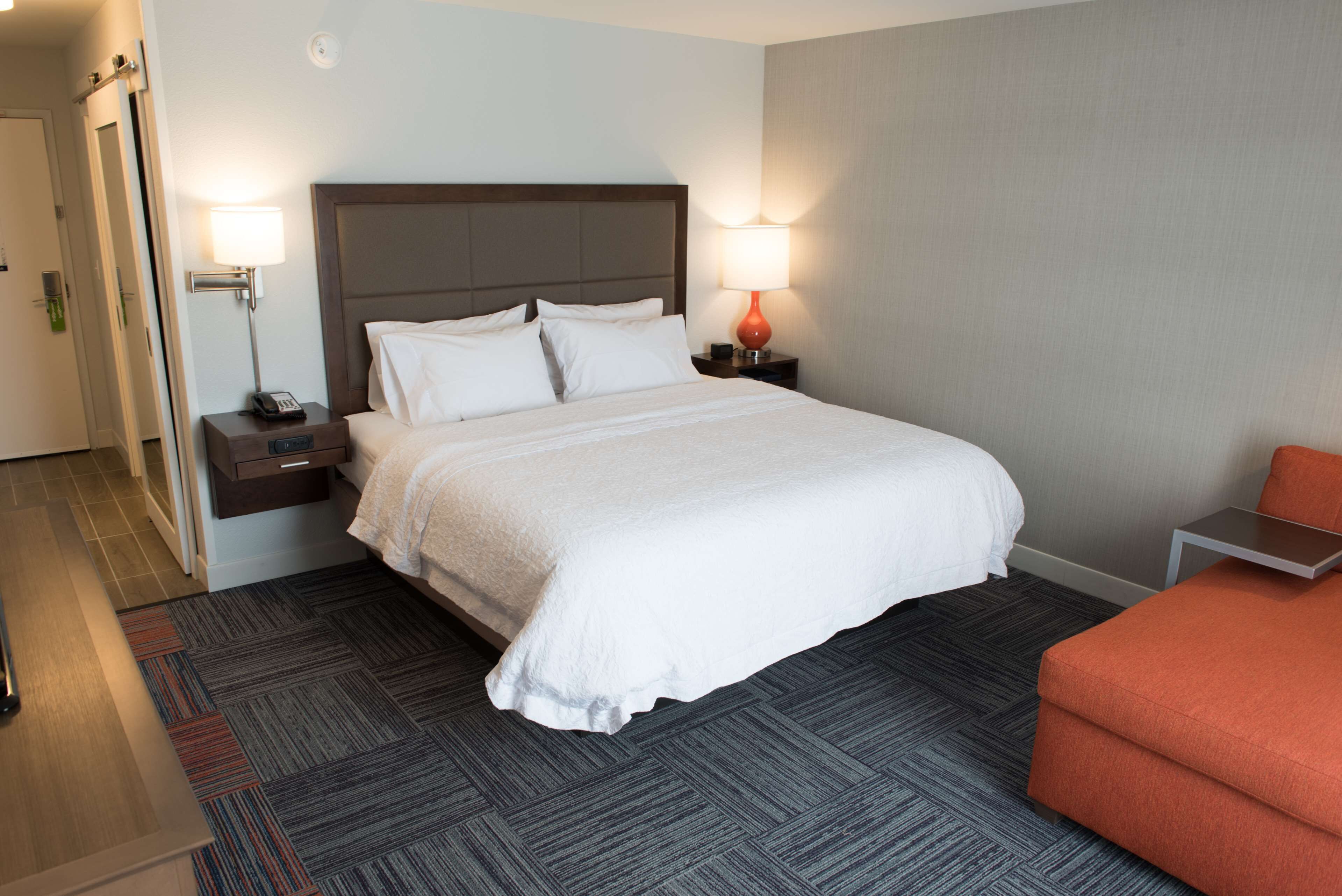 Een hotelkamer met een groot bed, twee nachtkastjes met lampen, een kleine tafel en een stoel.