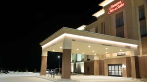 Un hôtel Hampton Inn & Suites doté d’un parking couvert, d’un panneau indiquant clairement une hauteur libre de 14 pieds et d’une façade en briques.