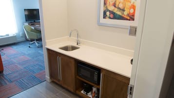 A modern kitchen with a built-in microwave, a sink, and a coffee maker.