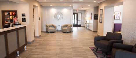 A hotel lobby with a reception desk, seating area, and a decorative wall piece.
