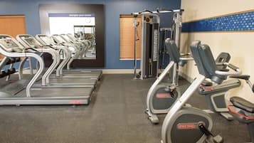 Un gimnasio con cintas de correr, elípticas y equipo de pesas.