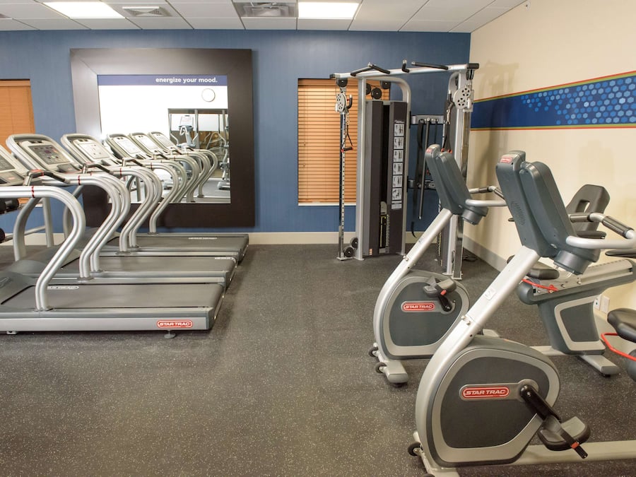 Un gimnasio con cintas de correr, elípticas y equipo de pesas.