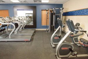 Un gimnasio con cintas de correr, elípticas y equipo de pesas.