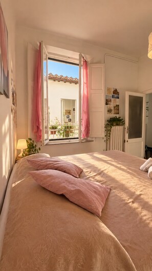 A bedroom with a bed, a window with curtains, a radiator, and a door. - Casa di Osio (Siena)