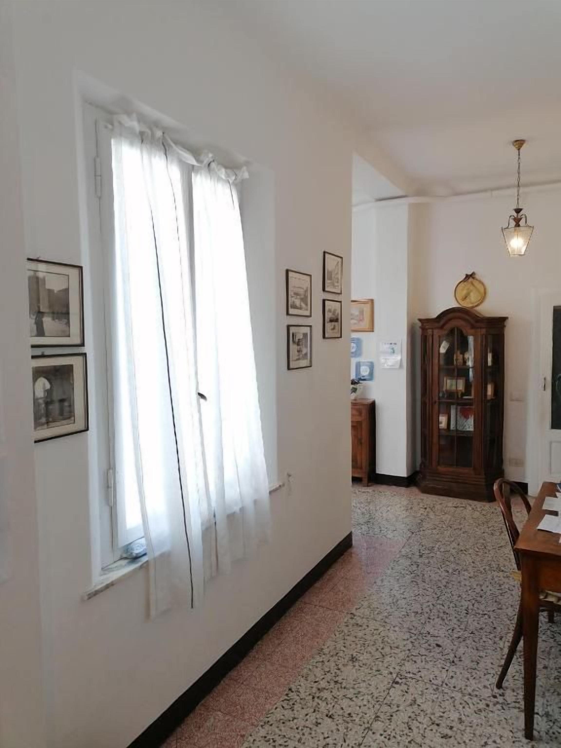 Un pasillo con una mesa de comedor y sillas, un reloj en la pared y cuadros enmarcados.