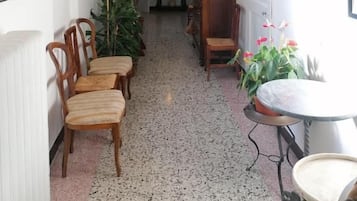 Un corridoio con sedie, un tavolo e piante in vaso.