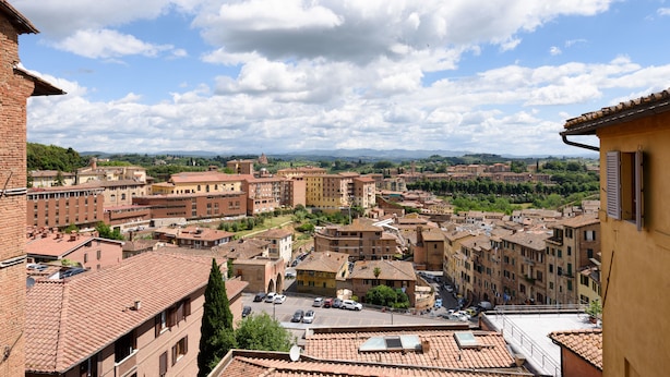 A view of a town with terracotta-roofed buildings, a clear sky, and distant mountains. - Casa di Osio (Siena)