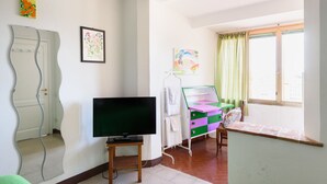 A room with a television, a mirror, a dresser, and a window with curtains. - Casa di Osio (Siena)