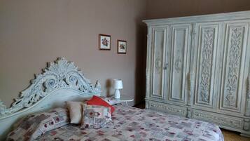 Una camera da letto con un letto grande e decorato, un armadio bianco e due quadri appesi al muro.