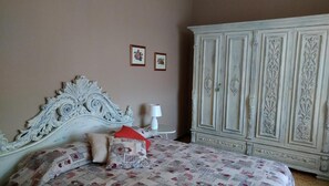 A bedroom with a large ornate bed, a white wardrobe, and two framed pictures on the wall. - Casa di Osio (Siena)