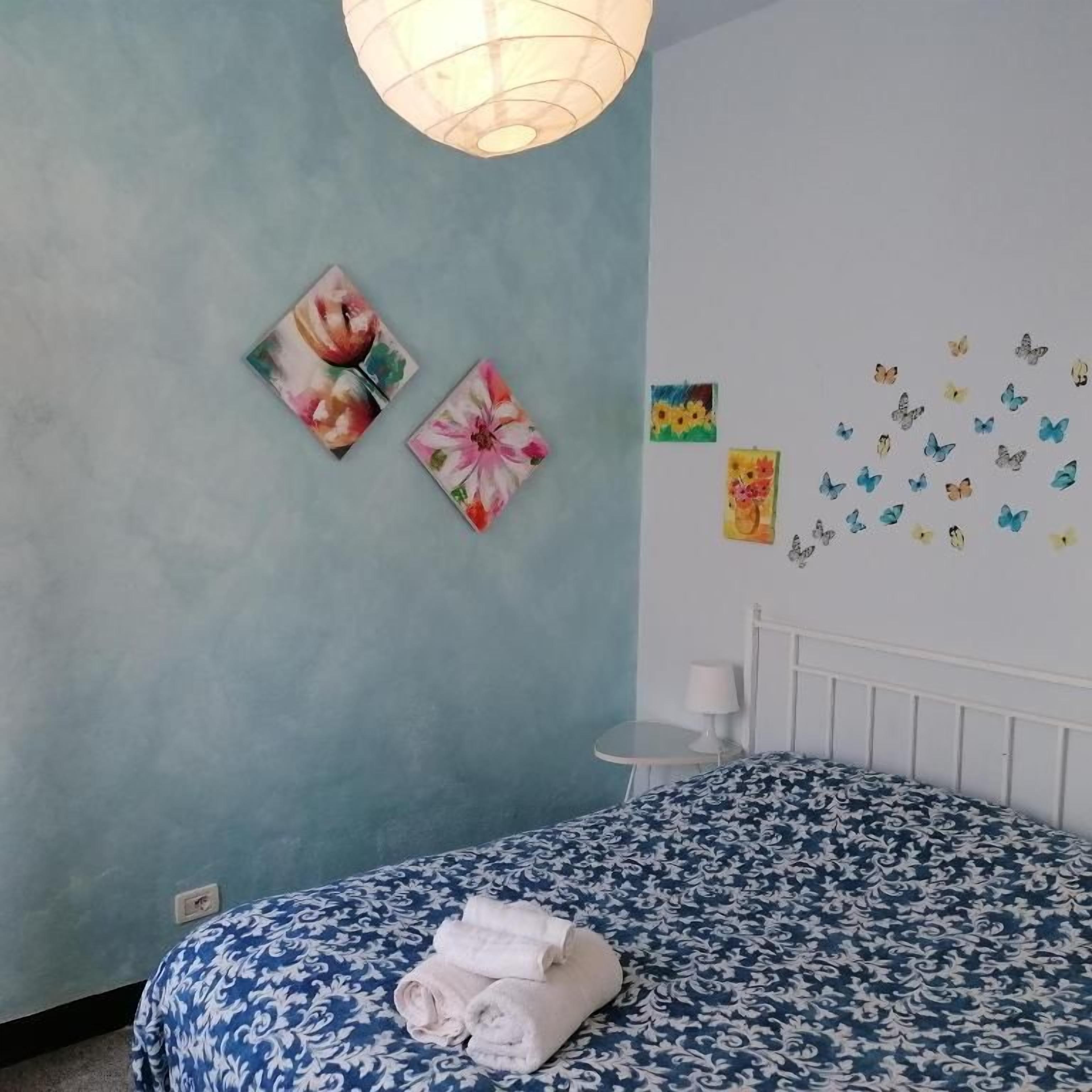 A bedroom with a bed, a wall-mounted lamp, and wall art.
