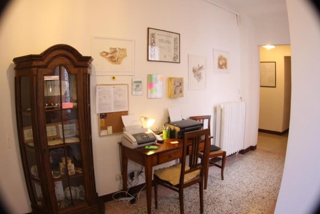 A room with a wooden desk, chair, and a cabinet with glass doors.