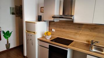 Una cocina moderna con encimera de madera, pileta de acero inoxidable y horno empotrado.
