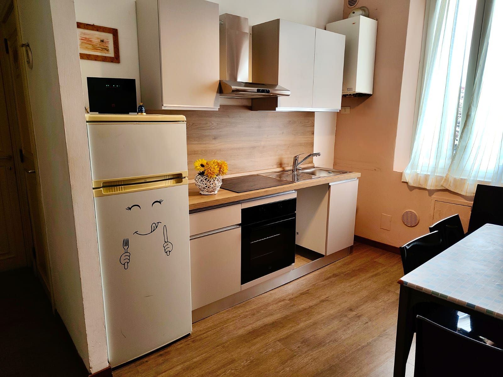 Cocina compacta con refrigerador, estufa, pileta y lavavajillas.