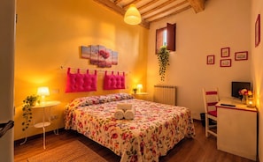 A cozy bedroom with a bed, bedside tables, a desk, and a chair.